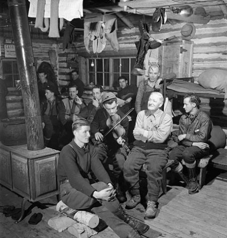 Lumbermen sitting around and enjoying violin music played by lumberman Romeo Clement of Farley Quebec in their bunk house